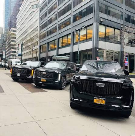 Three black Cadillac Escalades lined up in a downtown business district