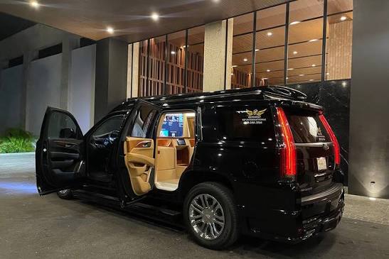 Black Escalade with door open at a hotel entrance at night